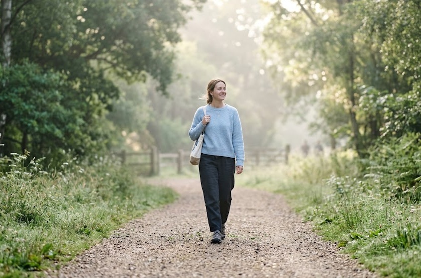 Persona che cammina con leggerezza su un sentiero luminoso al mattino presto